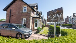 A traditional stone house with a sign reading "AYE STAY HOME" and a parked car in front. - Inverness (Inverness)