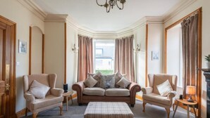 A spacious living room with a beige sofa set, a coffee table, and a fireplace. - Inverness (Inverness)