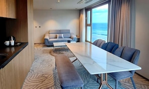 Quarto de hotel moderno com uma grande mesa de jantar, um sofá e vista para o oceano.