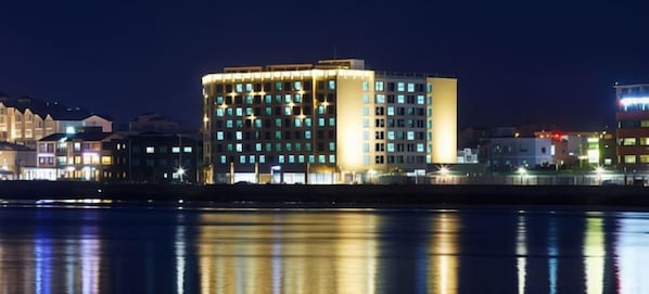 Um hotel de vários andares com design moderno, em localização de destaque na esquina e vista para o mar.