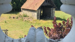 A rustic stone building with a sloped roof, surrounded by greenery and a clear sky. - La Lézardière (Épeigné-les-Bois)