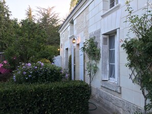 A white building with a garden area, including a hedge and flowering plants. - La Lézardière (Épeigné-les-Bois)