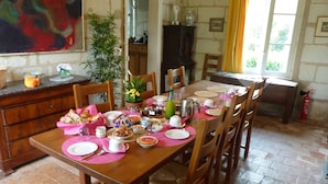 A dining area with a wooden table set for a meal, surrounded by chairs. - La Lézardière (Épeigné-les-Bois)