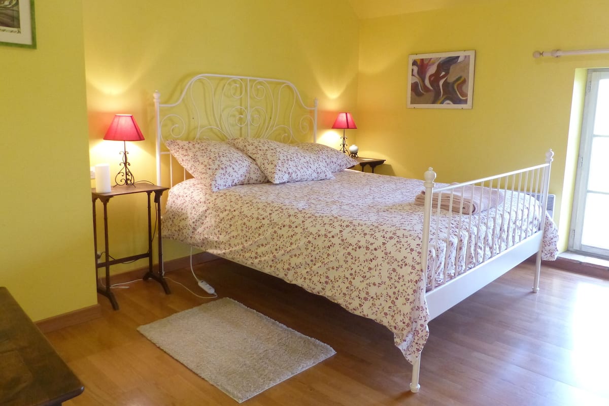 A bed with a white metal frame, a floral bedspread, and two bedside lamps with red shades.