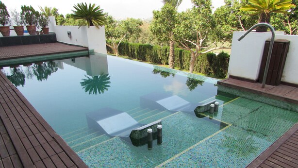 A rectangular infinity pool with a tiled edge, surrounded by a wooden deck.
