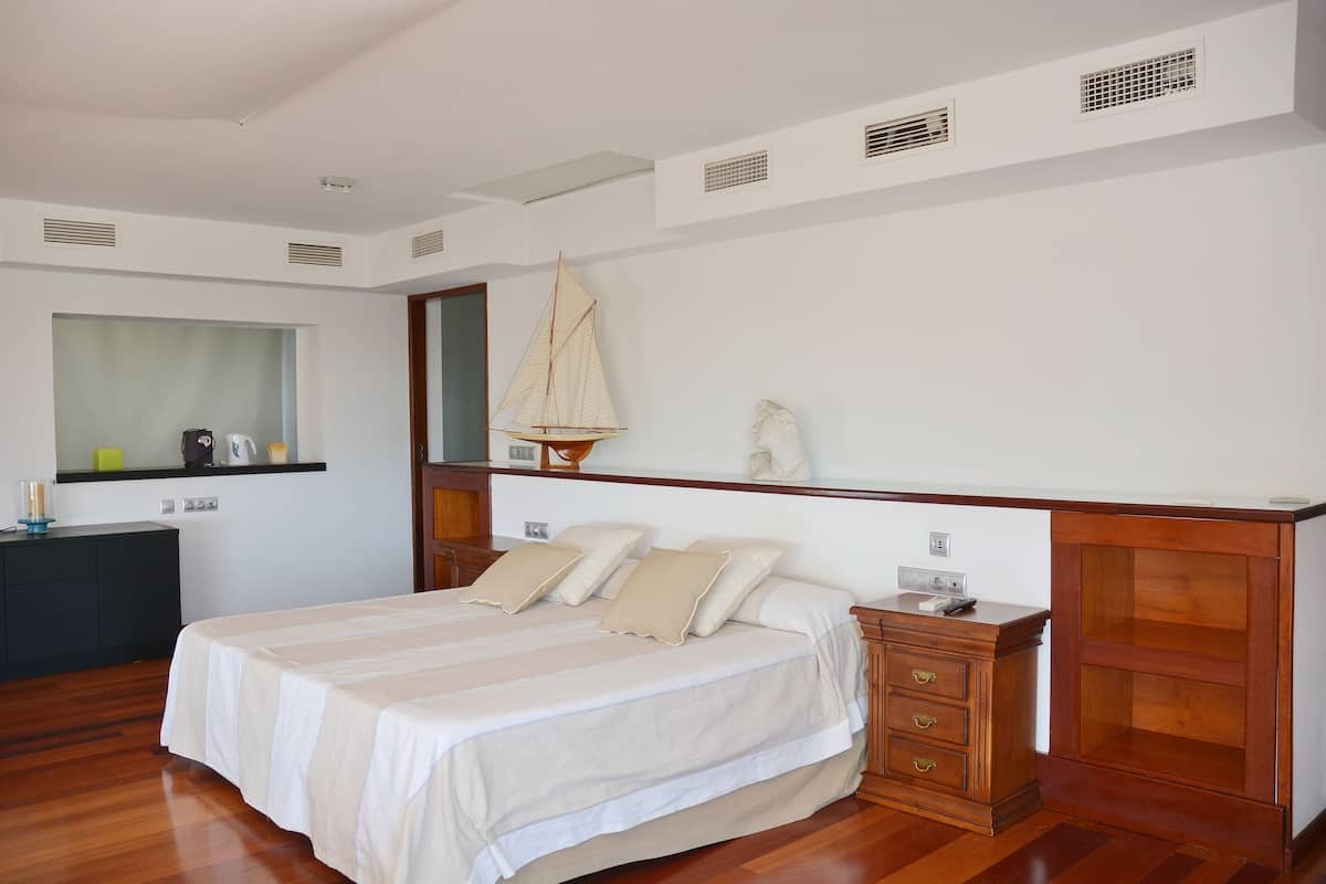 A bedroom with a large bed, wooden headboard, a dresser, and a wall-mounted sailboat decoration.