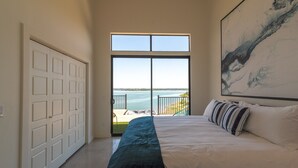 Ein Schlafzimmer mit einem großen Bett, Meerblick und einer Tür zu einem Balkon.