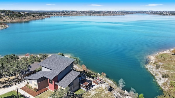 Una casa con una amplia terraza que da a un lago tranquilo.