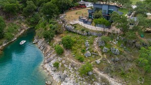 Ein modernes Haus mit Pool, eingebettet in eine natürliche Landschaft und einer Wasserfläche.