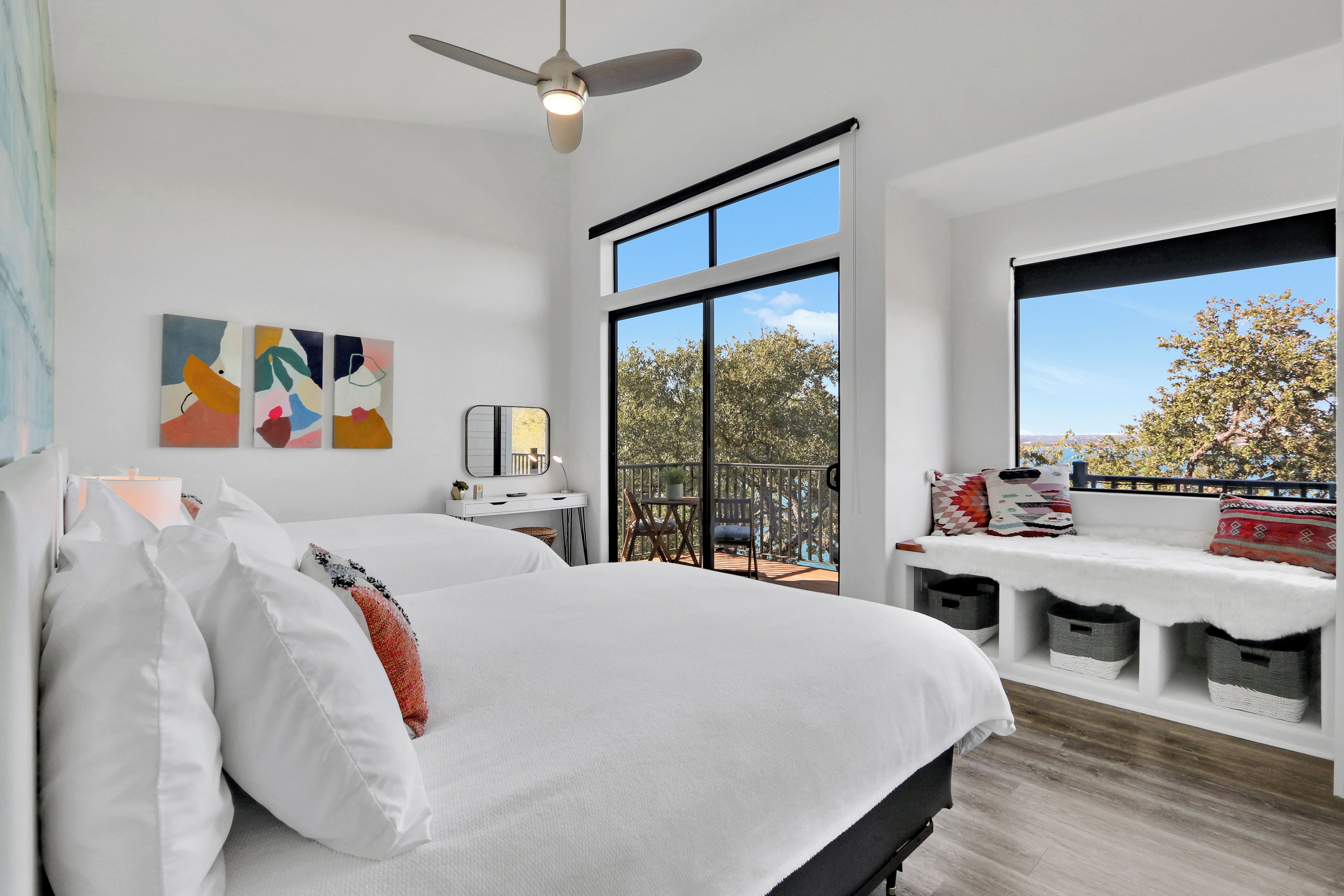 A modern bedroom with a large bed, a desk, and a balcony with a view.