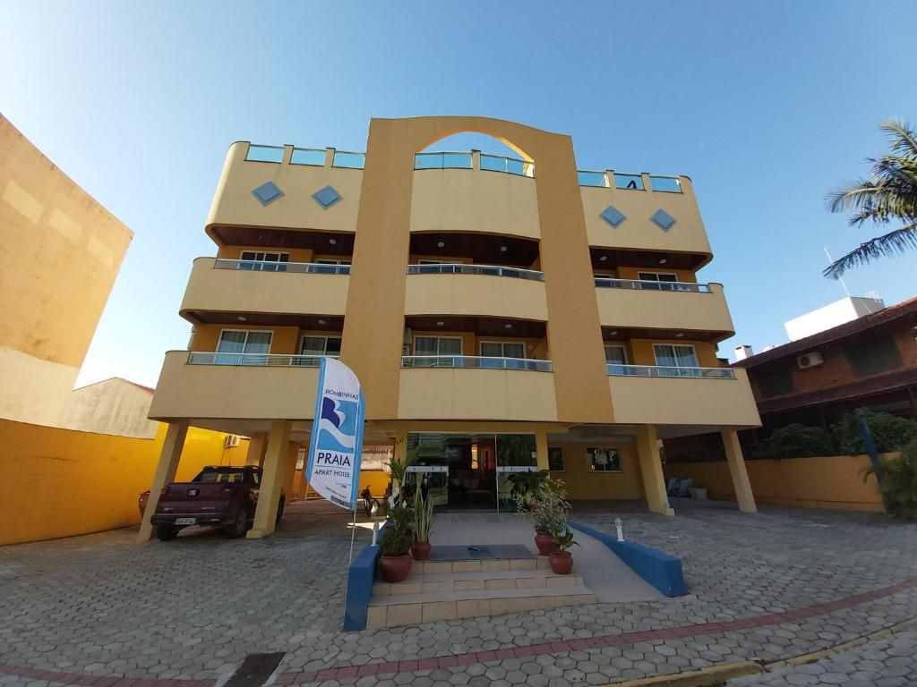 A multi-story building with a central entrance, balconies, and a sign indicating a parking area.