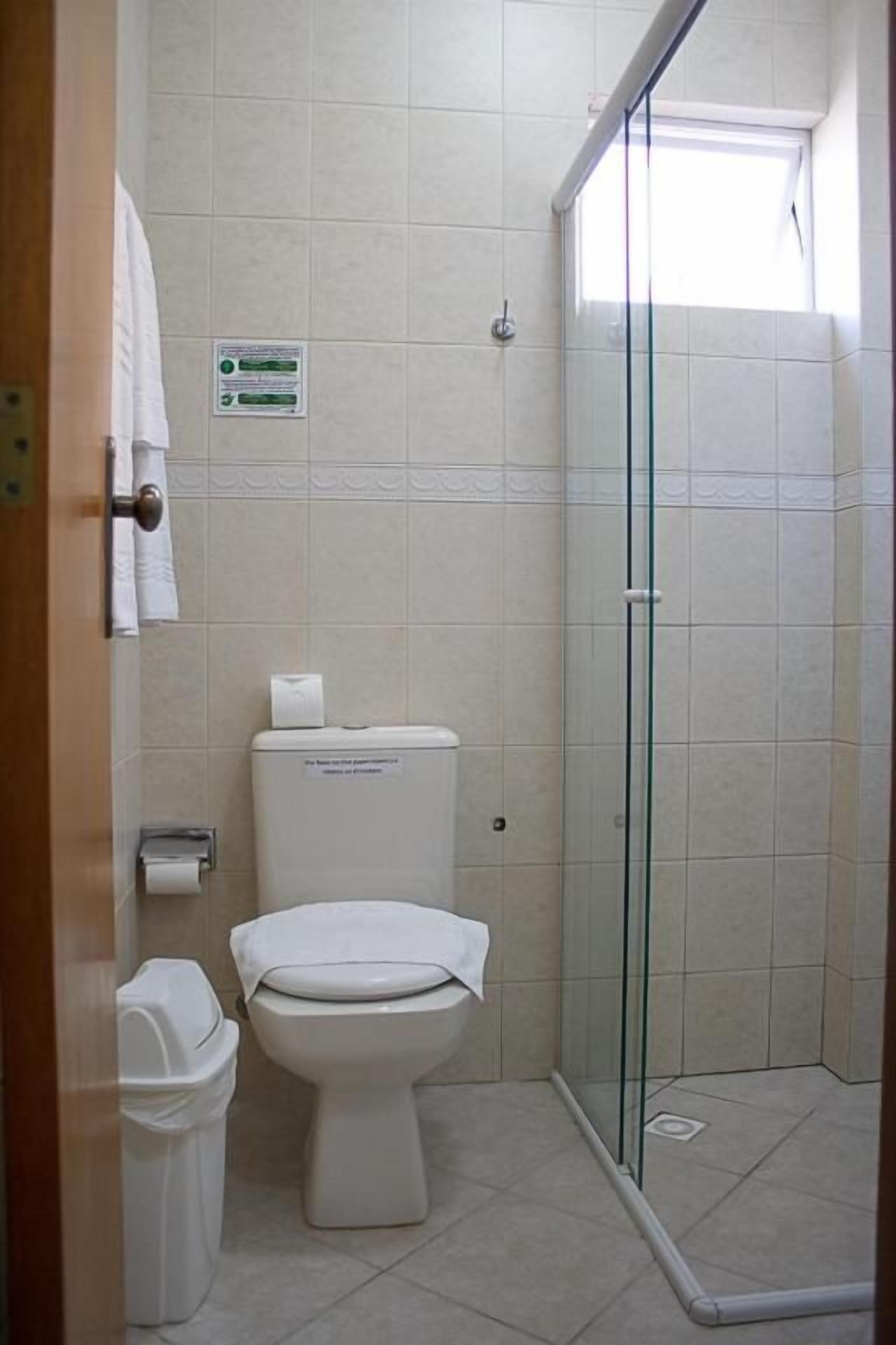 Un baño con inodoro, cabina de ducha de vidrio y lavamanos blanco.
