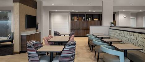 A modern restaurant with booths and tables, a flat-screen TV mounted on the wall, and a counter area.