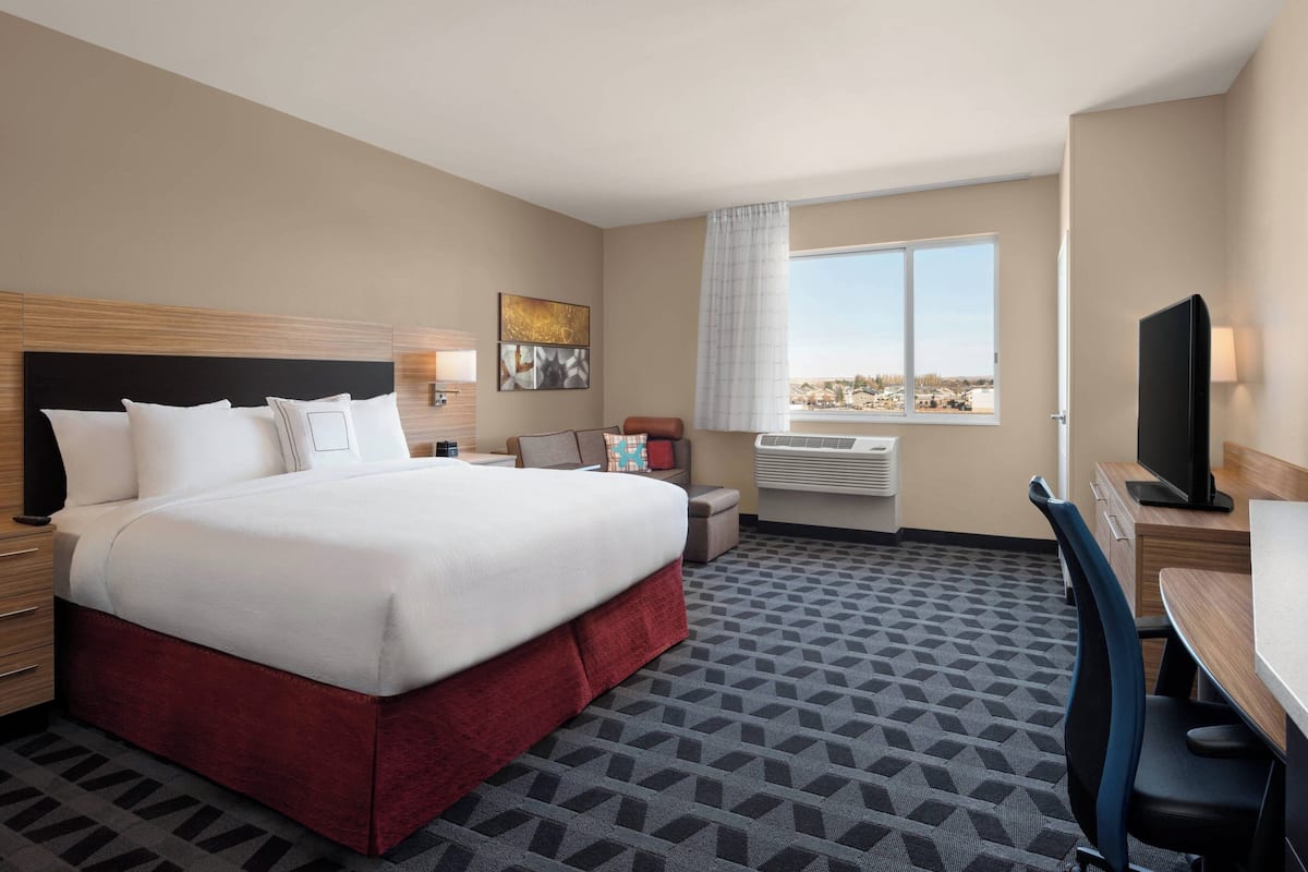 Hotelkamer met een groot bed, een bureau, een stoel, een televisie en een raam met uitzicht op de stad.