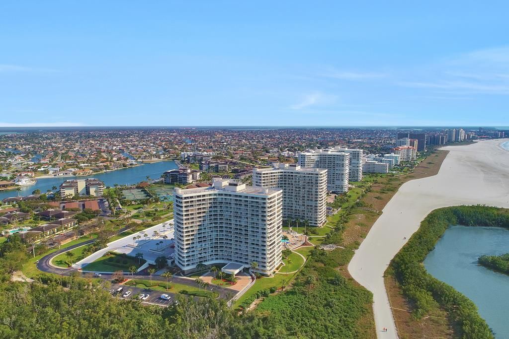 Ein Hochhaus-Hotel mit mehreren Etagen, einem Parkplatz und Blick auf den Strand.