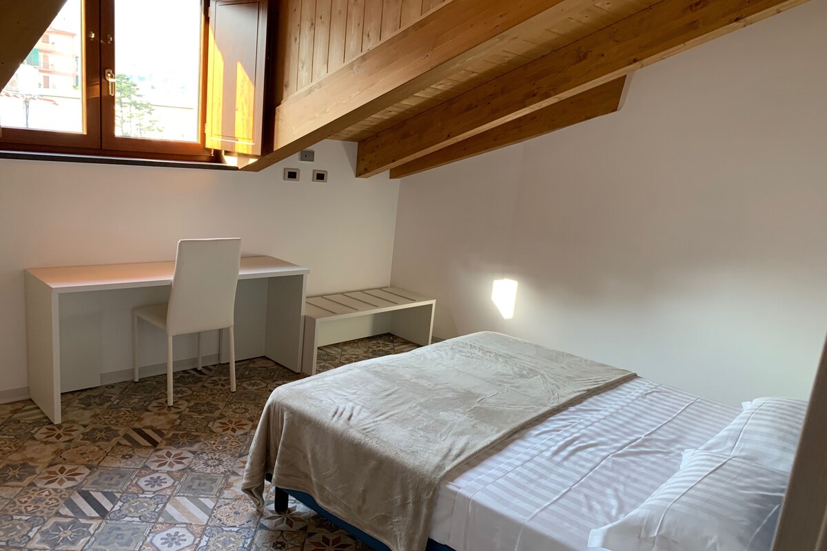 Un dormitorio con una cama, un escritorio y una silla.