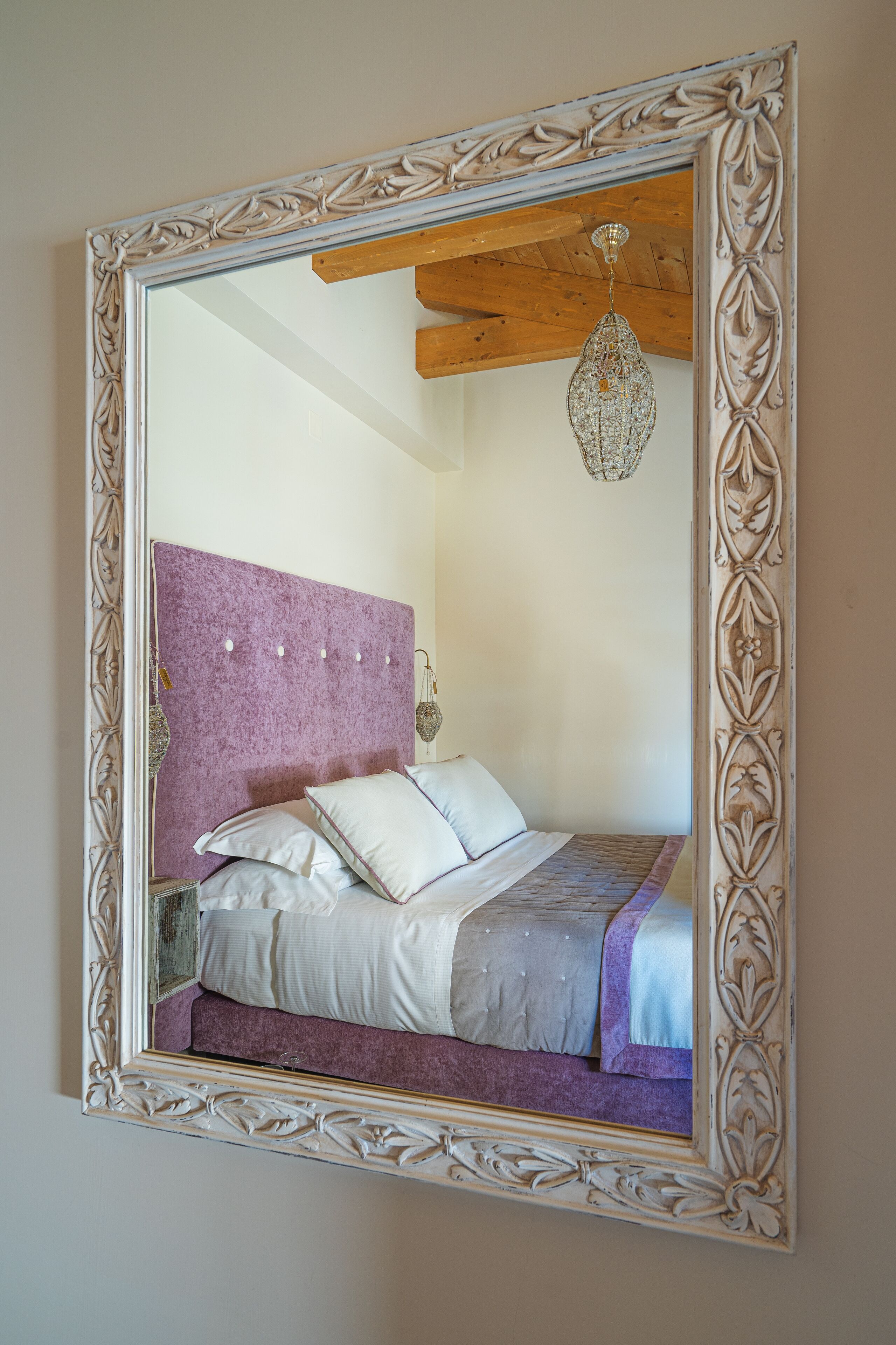A bedroom with a large mirror, a wooden ceiling, and a hanging light fixture.