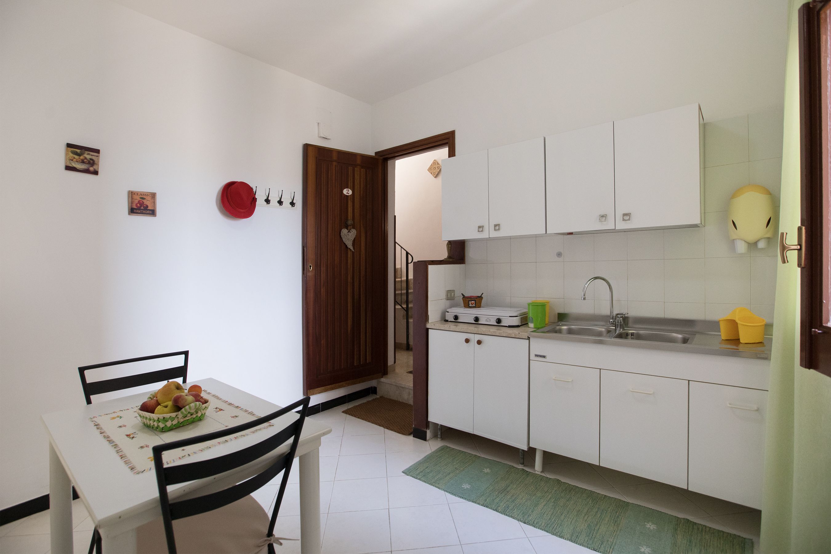 A small, clean kitchen with white cabinets, a sink, and a dining area with a table and chairs.