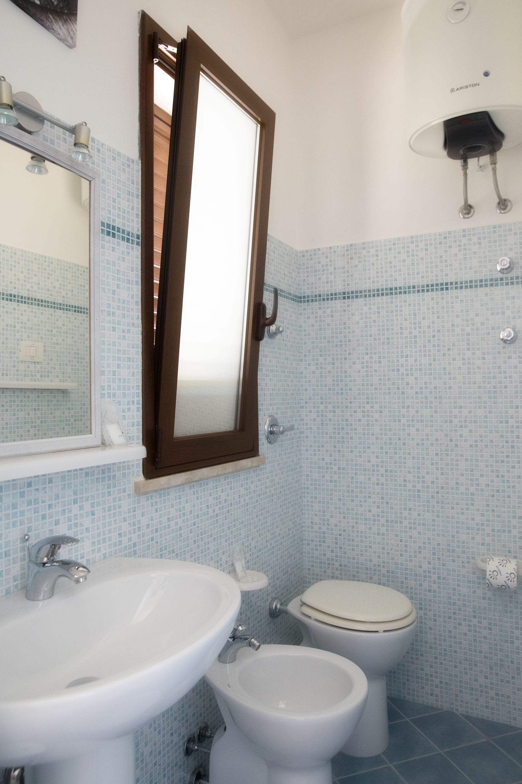 Un baño con lavamanos, inodoro y espejo.