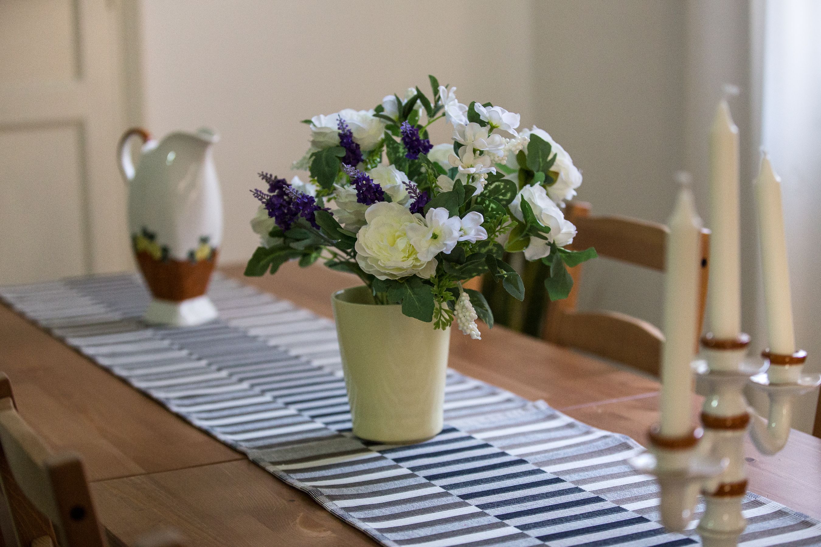Una mesa de comedor con un jarrón de flores, una jofaina y velas.