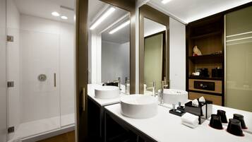 A modern bathroom with two sinks, a shower, and a mirror.