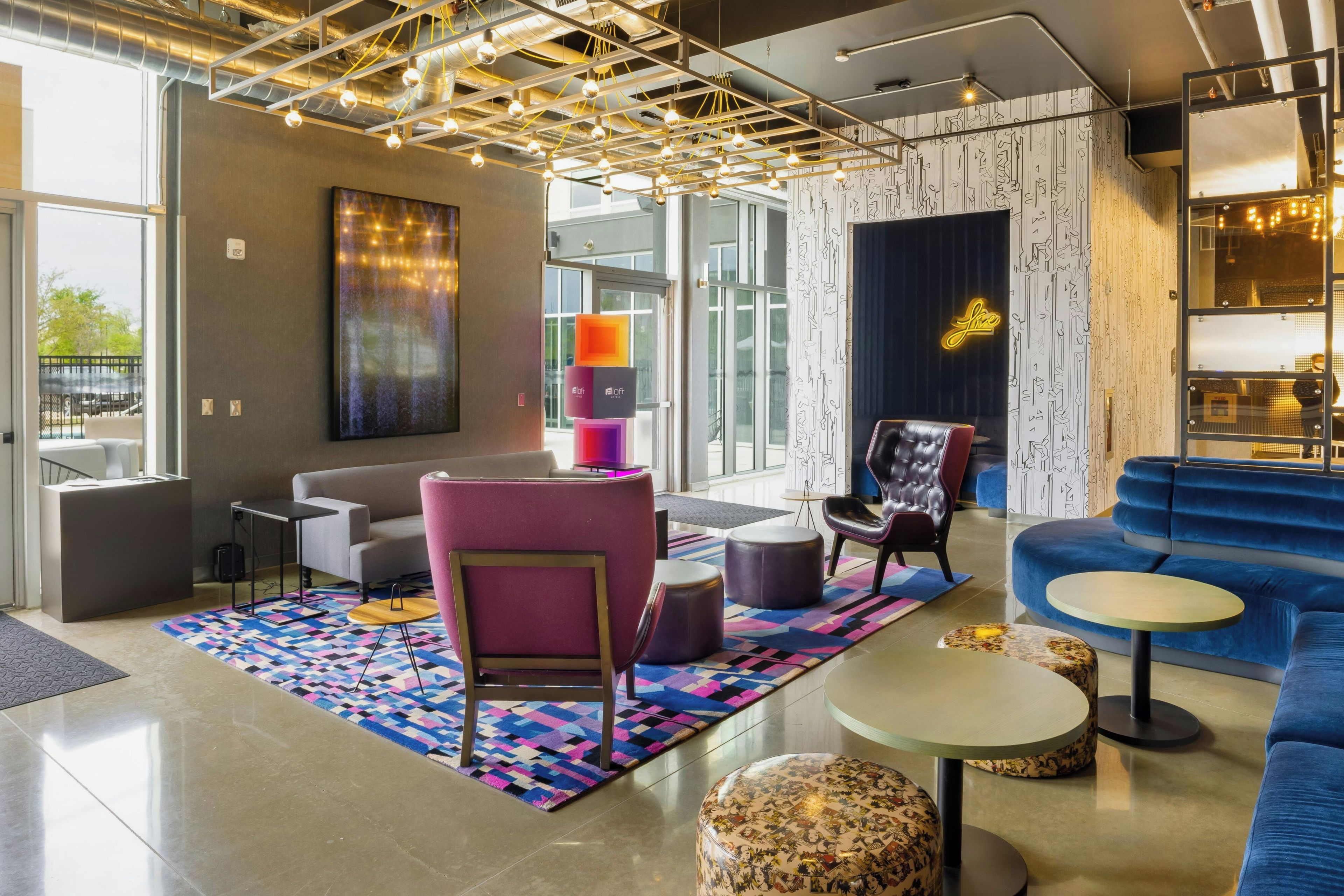 A modern lounge area with a sofa, chairs, a coffee table, and a patterned rug.