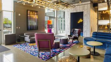 A modern lounge area with a sofa, chairs, a coffee table, and a patterned rug.