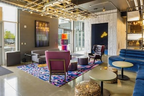 Un espacio lounge moderno con un sofá, sillas, una mesa de centro y una alfombra estampada.
