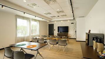 A conference room with a large TV screen, multiple tables, and chairs.