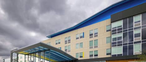 A modern hotel with a covered entrance, large windows, and a flat roof.