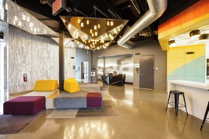 A modern lobby with a reception desk, seating area, and a visible elevator.