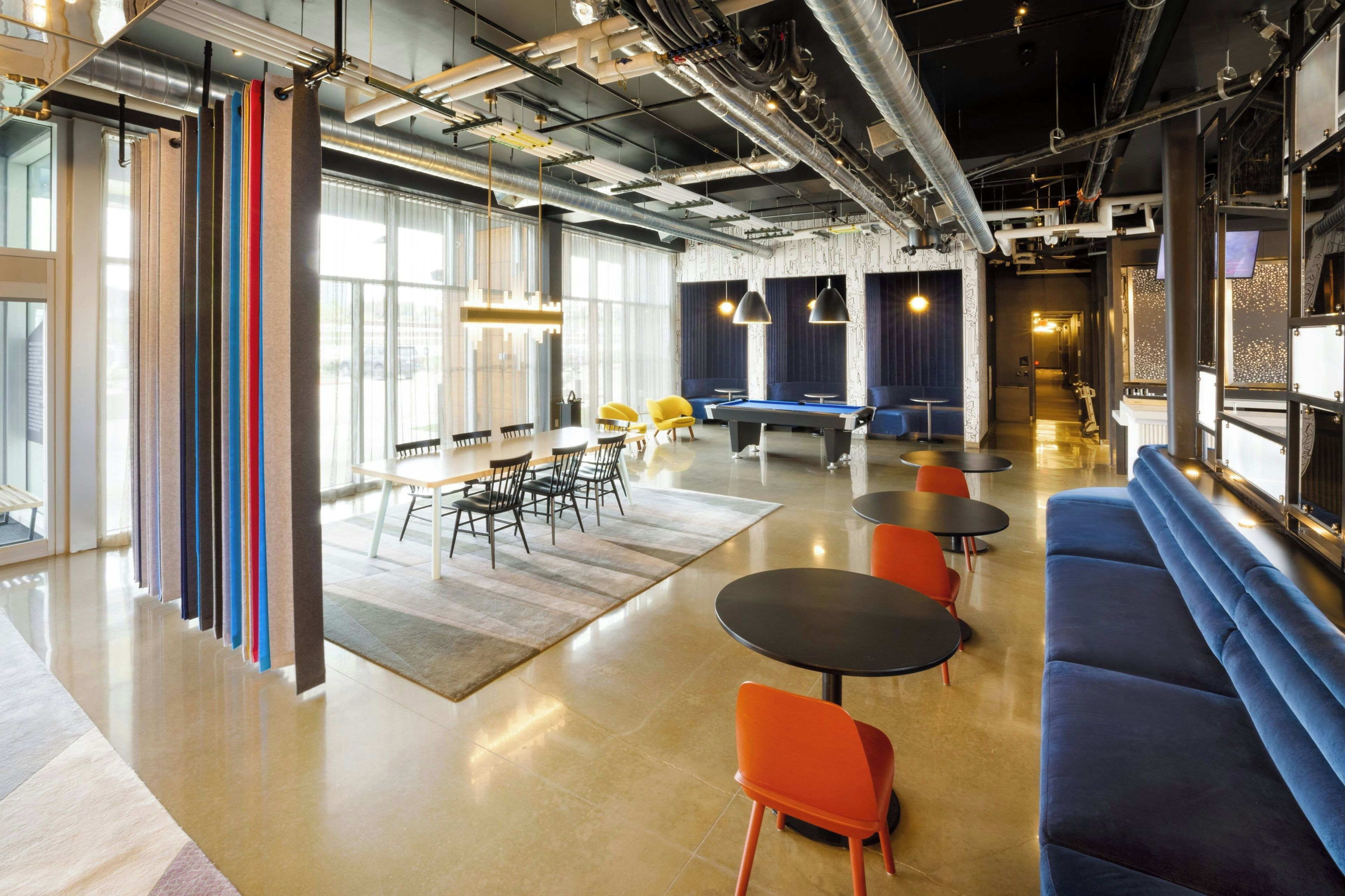 A modern lounge area with a pool table, seating, and a large window providing natural light.