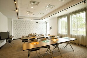 A conference room with a marble-patterned wall, a television on the left, and a large window on the right. - Aloft by Marriott Austin Airport (Austin)