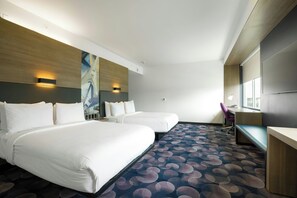 Habitación de hotel con dos camas, un escritorio, una silla y un ventanal grande.