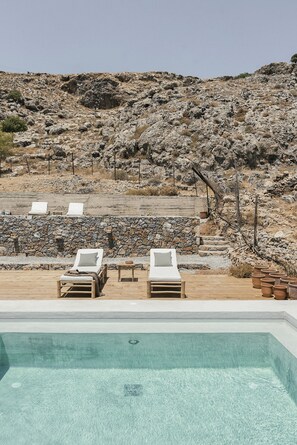 Relax by the serene pool surrounded by a natural rocky landscape and comfortable loungers.