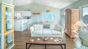 A spacious living area with a sofa, coffee table, and a view of the kitchen and dining area. - Blue Haven | Ocean Views, Private Pool + Beach Access! (Surf City)