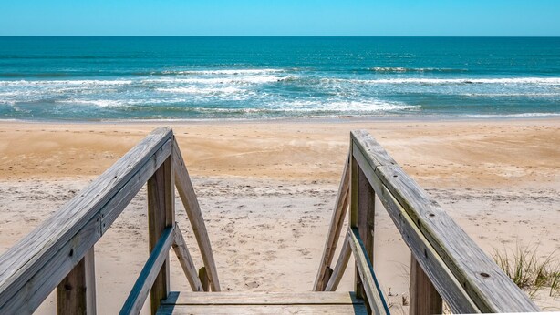 A wooden boardwalk leading to a beach with clear blue water and a sandy shore. - Blue Haven | Ocean Views, Private Pool + Beach Access! (Surf City)
