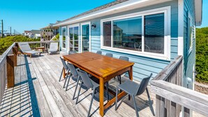 A wooden deck with a table and chairs, a covered patio area, and a view of the ocean. - Blue Haven | Ocean Views, Private Pool + Beach Access! (Surf City)