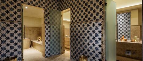 Une salle de bain avec des murs à motifs, un miroir et un lavabo avec des articles de toilette.