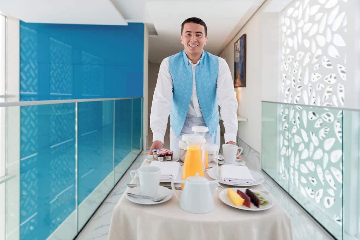 A breakfast setup with a table, breakfast items, and a person in a blue vest.