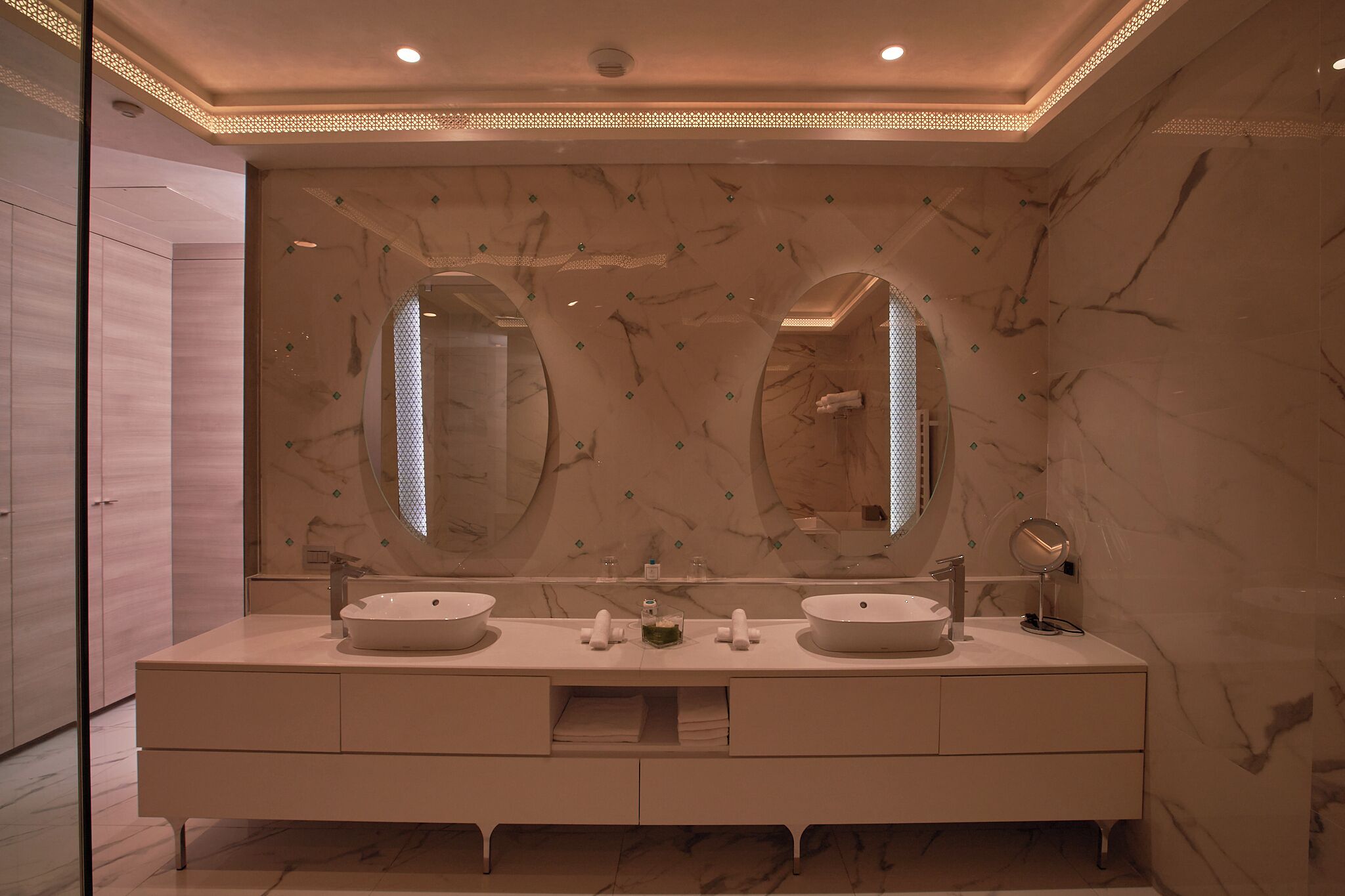Un baño moderno con dos lavamanos, espejos grandes y un salpicadero de mármol.