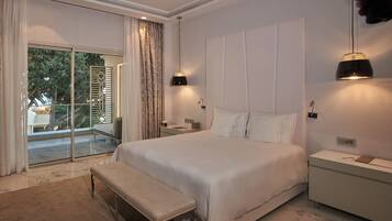 A spacious bedroom with a large bed, a bench, a nightstand, and a bedside table.