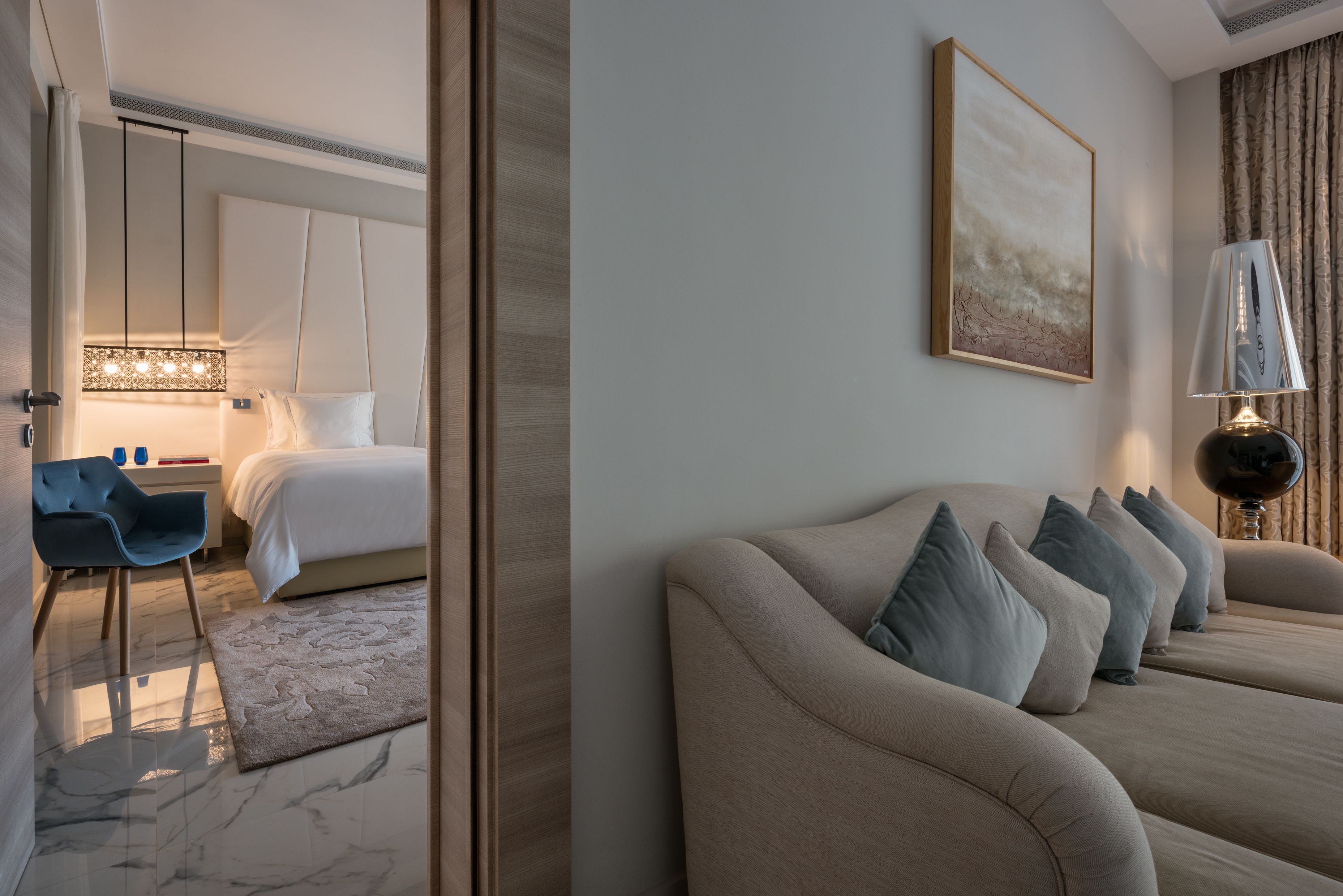 A modern hotel room with a bed, a sofa, a desk, and a chair.