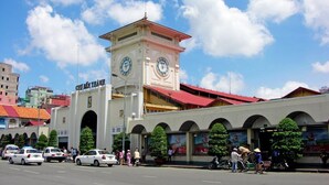 Una torre de reloj con un letrero que dice "Cuu Ruc Thanh" frente a un edificio con ventanas de arco.