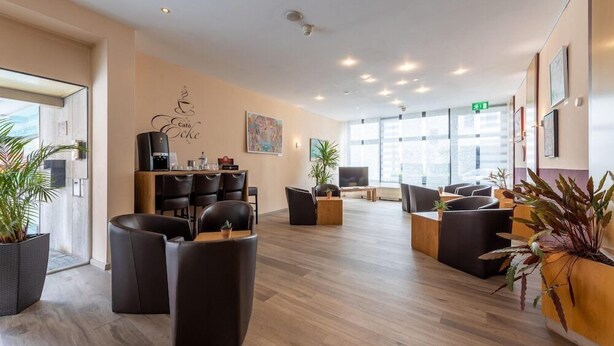 A spacious lobby with modern furniture, a coffee machine, and large windows allowing natural light. - Trip Inn Frankfurt Airport Russelsheim (Ruesselsheim)