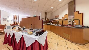 A buffet setup with a variety of food items and beverages, a wooden counter, and a tiled floor. - Trip Inn Frankfurt Airport Russelsheim (Ruesselsheim)