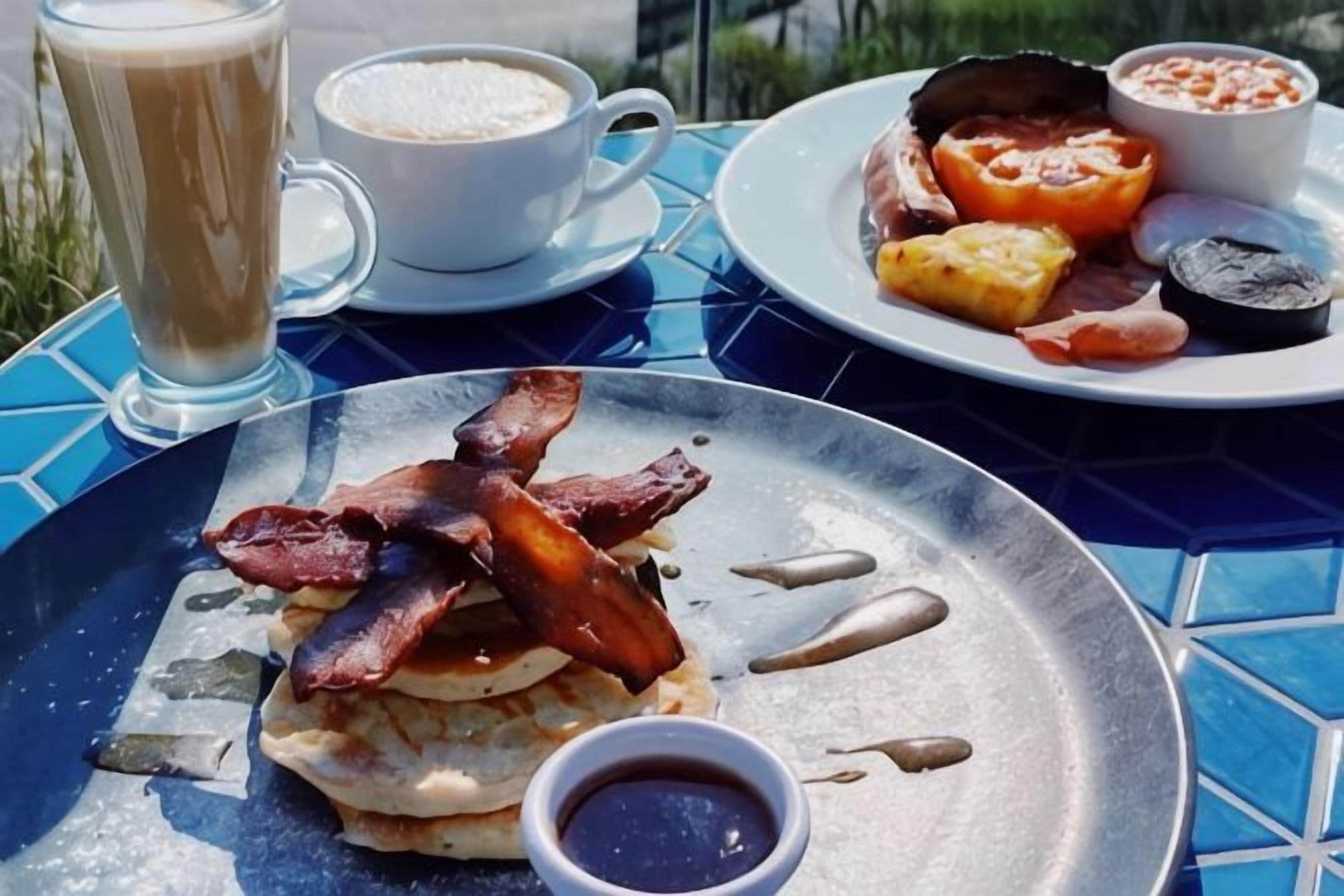 Ein Frühstückstisch mit Pfannkuchen, Speck, Kaffee und dazu Eiern.