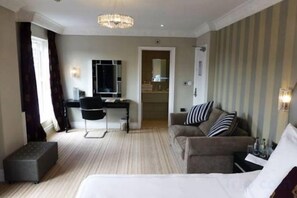 A hotel room with a bed, a desk, a chair, a sofa, and a small ottoman. - Great National Cliff Hotel (GREAT YARMOUTH)