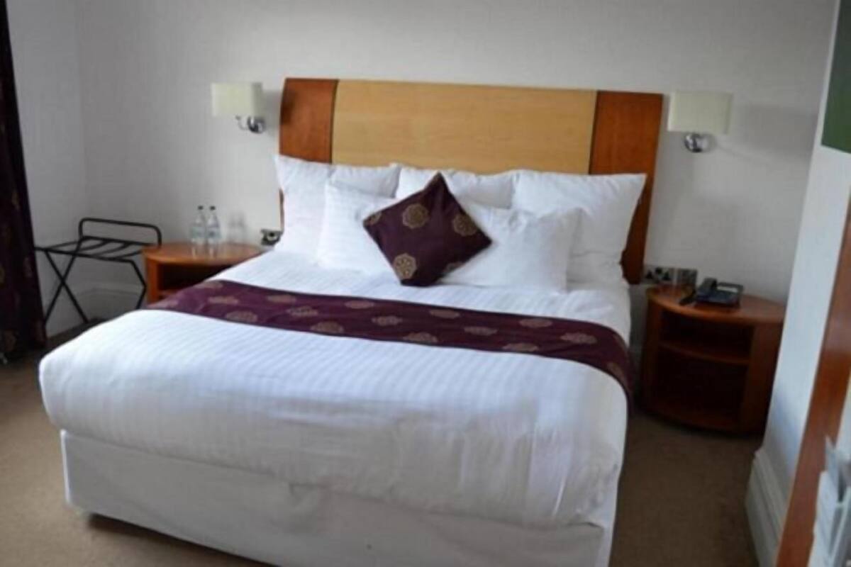 Una habitación de hotel con una cama, una mesita de noche, una lámpara y una pequeña mesa.