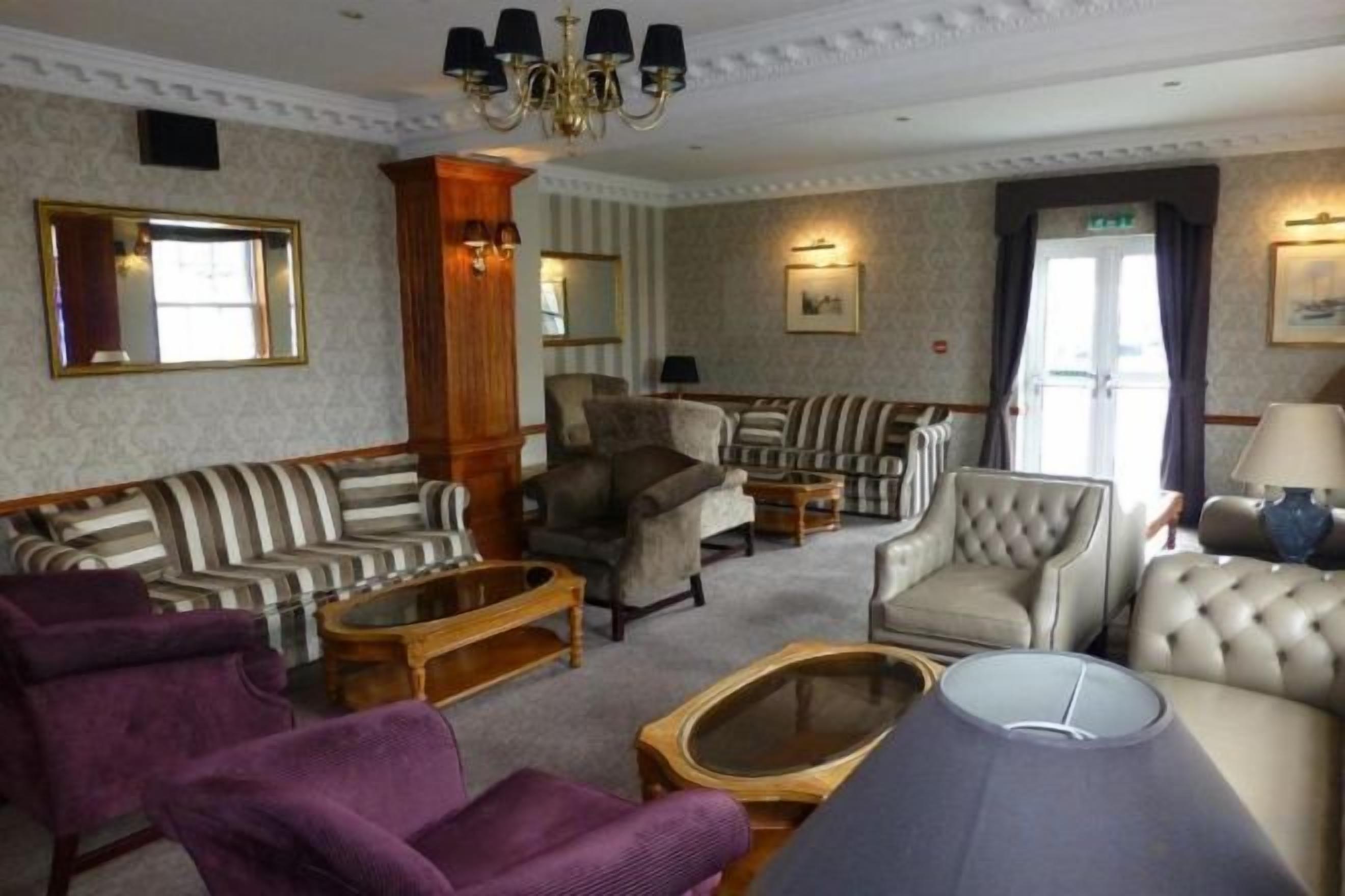 A hotel lounge with striped sofas, armchairs, a tufted sofa, and a coffee table.